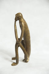Side view of the vintage bronze monkey highlighting its pensive pose and silhouette.