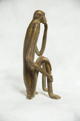 Side profile of the vintage bronze monkey showing its slender, thoughtful pose.
