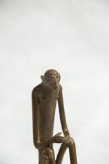 Stylized face and slender torso of a vintage African bronze monkey sculpture showing an aged patina.