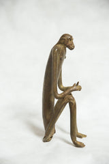 Vintage bronze monkey sculpture with a slender body, viewed from the side.