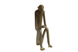 Vintage African bronze sculpture of a seated monkey with an elongated body and hands touching.