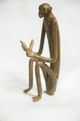 Side profile of the vintage bronze monkey showing its elongated limbs and seated pose.