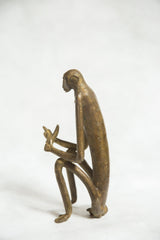 Vintage bronze monkey sculpture in profile, showing its slender, elongated form.