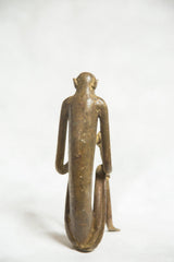 Rear view of the cast bronze monkey sculpture, showing its elongated form and aged patina.