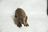The textured head and front paws of a vintage cast-bronze pangolin sculpture.