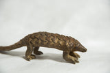 Full profile of a vintage bronze pangolin showing its articulated scale texture.