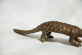 Close-up of the long tail and scaled hindquarters of the bronze pangolin sculpture.