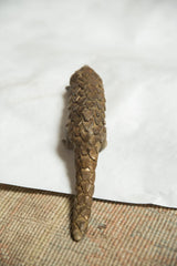 Articulated bronze scales run down the back and tail of the pangolin figure.
