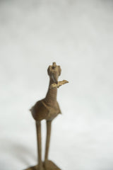 Aged bronze fishing bird sculpture detail, focusing on its head, beak, and fish.