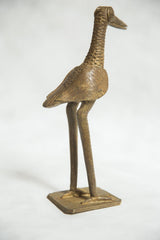Detail of vintage African bronze bird sculpture's square base and slender legs.