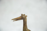 The stylized head of a vintage African bronze bird featuring large round eyes and three horns.