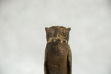 Vintage African bronze owl's intricately detailed head holding a rodent, with textured finish.