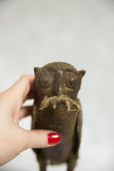 Close-up of vintage African bronze owl holding rodent, intricate face detail, aged patina.