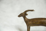Close-up of vintage African bronze antelope head, showcasing spiral horns and aged texture.