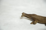 Detailed view of the vintage bronze crocodile's textured head with a fish in its open jaw.