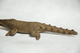 Bronze African crocodile sculpture displaying textured scales along its body and tail.