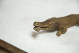 Textured bronze African crocodile sculpture close-up, with fish in mouth.