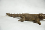 Detailed texture of the cast bronze crocodile's back and tapering tail.