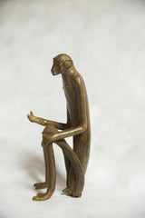 Side profile of vintage African bronze monkey sculpture, hand extended as if speaking.