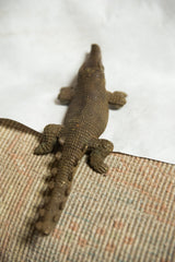 High-angle view of the vintage bronze crocodile's detailed, textured back and imperfect snout.