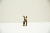 Frontal view of a vintage bronze Ashanti rabbit showing its stylized face and long ears.