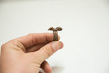 Profile view of the vintage African copper ring's textured band and reclining figures.