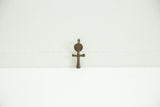The textured surface and dark aged patina of a vintage African bronze cross charm.