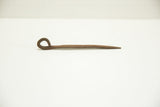 Dark, oxidized patina on a vintage African hand-cast nail with a looped head.