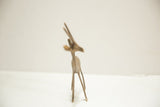 Vintage African bronze gazelle, slender body and long legs from an angled view.