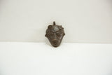 Sculptural details and time-softened patina on a vintage African bronze face charm.