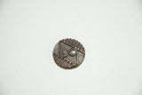 A round African bronze coin featuring incised double-spiral motifs and a deep, aged patina.