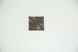 Square African bronze coin featuring a divided geometric pattern with varied lines and natural patina.