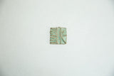 Vintage bronze coin showing heavy turquoise-green oxidation over its incised design.