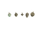A row of five vintage African bronze tiny face pendants showing variations in design and patina.