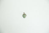 A vintage bronze face pendant with stylized features and visible green aged patina.