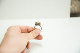 Hand displaying a unique vintage African bronze ring with a sculpted, patinated top.