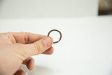 A vintage African bronze ring with a twisted design held between two fingers.