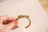 The Double Chameleon cuff bracelet held to show its handcrafted texture and aged patina.