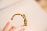 Profile view of the vintage brass chameleon bracelet, showing its open cuff design.