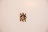 Reverse side of the flat turtle pendant showing its solid construction and aged brass patina.