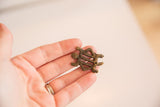 Vintage bronze turtle pendant held in hand to show its small scale.