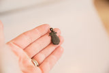 Textured bronze pineapple pendant held in hand to show its small scale.