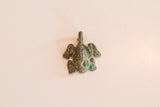 Overhead view of a vintage bronze African frog pendant with a textured green patina.