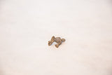 Angled view of a vintage African bronze frog charm with a rough, dusty patina.