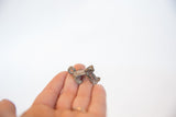 Vintage bronze frog pendant held in a hand to demonstrate its small charm size.