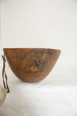 Vintage African bowl detail, showing a prominent crack with primitive repairs on aged wood.