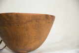 Visible cracks and aged, hand-carved wood texture of the African bowl.