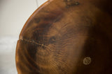 Hand-carved wood texture of the vintage African bowl, showing distinct grain, cracks, and a visible repair.