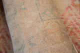 Detail of hand-knotted vintage rug fragment pile, featuring muted beige and faded blue patterns.