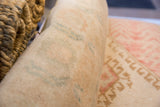 Detail of hand-knotted pile on rolled vintage Oushak pillow in muted beige and green.